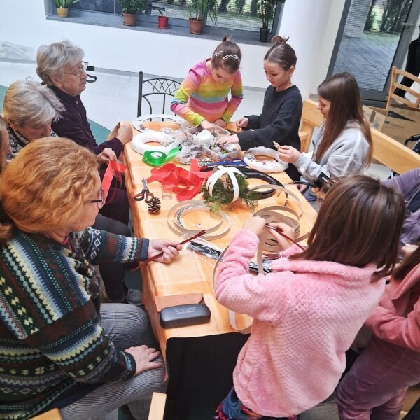 deti sa so seniormi pri stole venujú kreatívnym činnostiam
